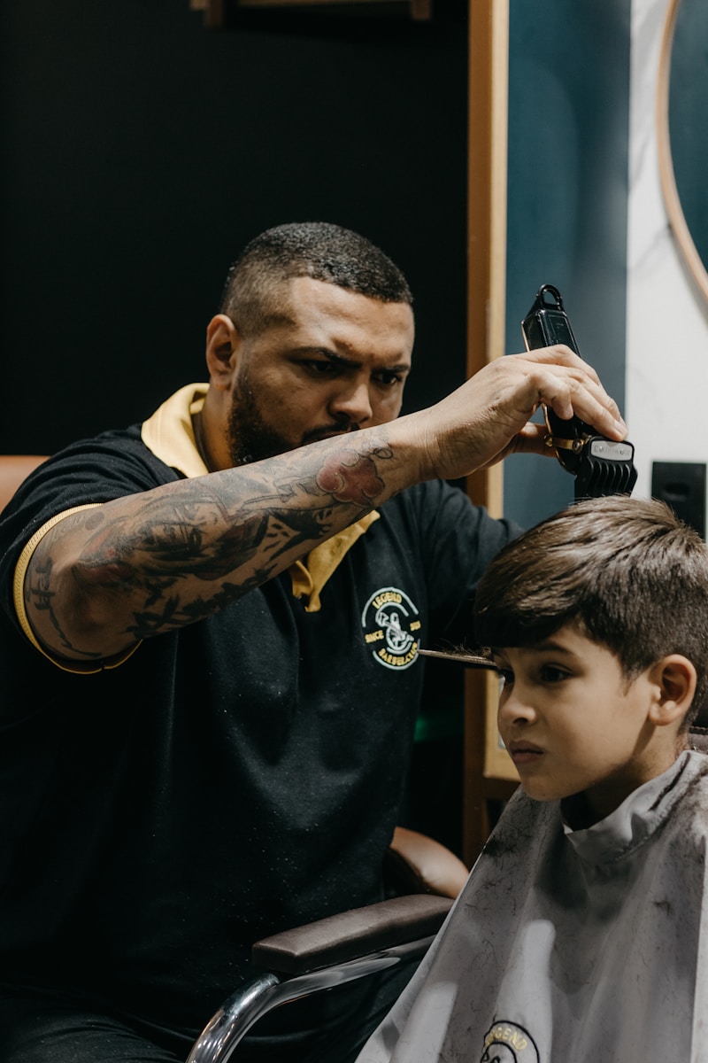 a man cutting a young boy's hair in a barber shop