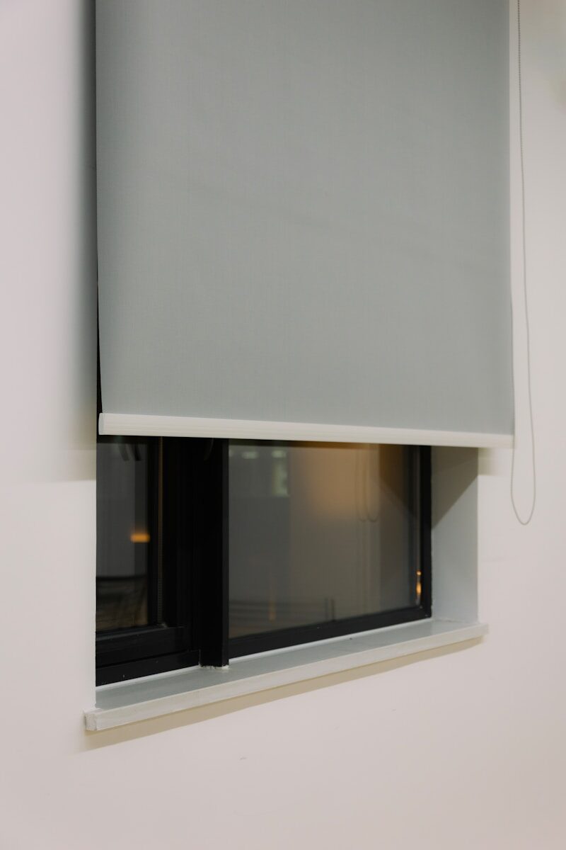 A gray roller blind partially covers a modern window.